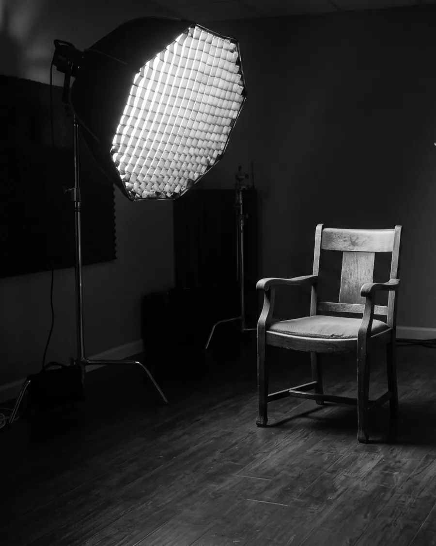 Cadeira vazia iluminada por uma luz lateral, preparada para uma entrevista documental