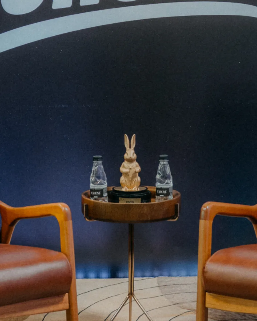 Mesa entre as poltronas com o trof&eacute;u dourado e garrafas de &aacute;gua
